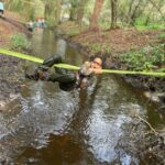 child hanging on rope over creek